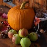 Ideen für Herbst Dekoration mit Kürbissen, Äpfeln, Kastanien, Walnüssen und bunten Blättern, rustikaler Hintergrund